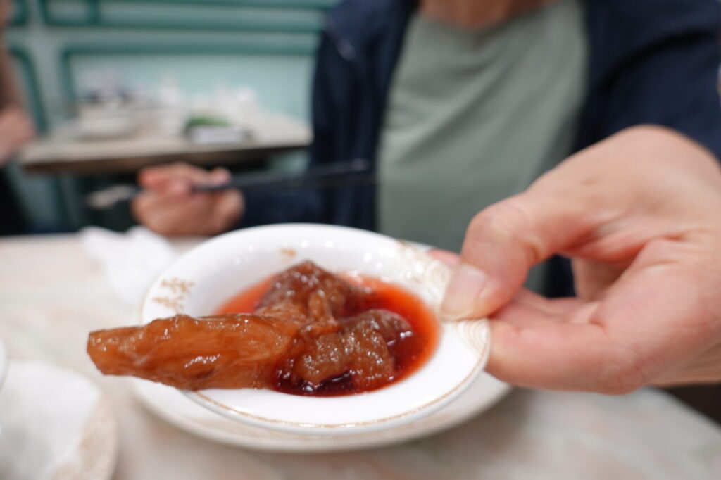 出典私ミシェリー@HKGlossy.comによる撮影. 麥奀雲吞麵世家の卓上にある調味料赤酢と醤油を小皿にとり、特效牛筋撈麺の牛筋をつけていただいているところ